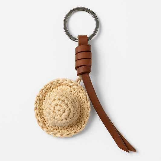 Keychain with woven round charm and brown leather strap on a white background
