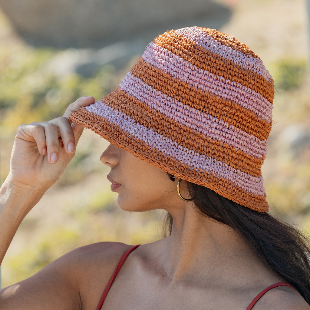 Woman wearing a striped bucket hat with a blurred natural background