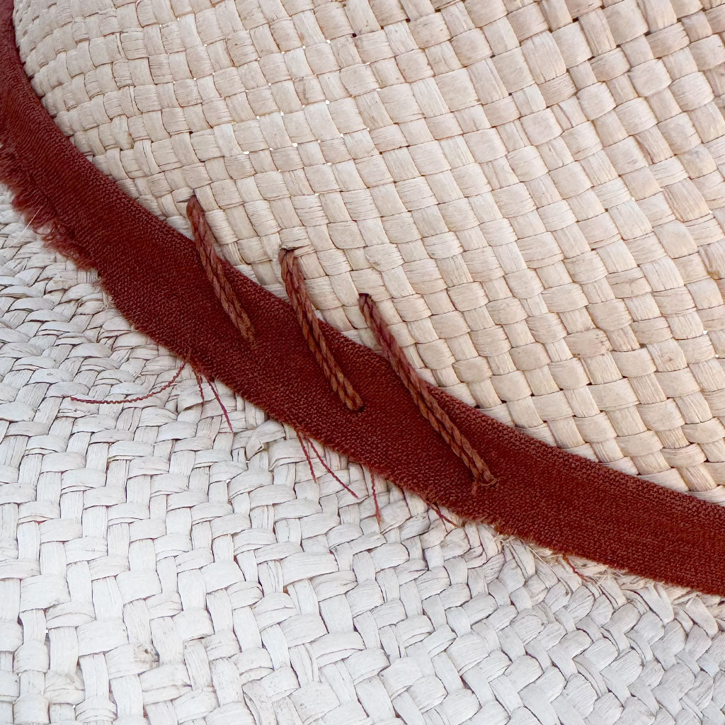 Close-up of a woven straw hat with a dark red band