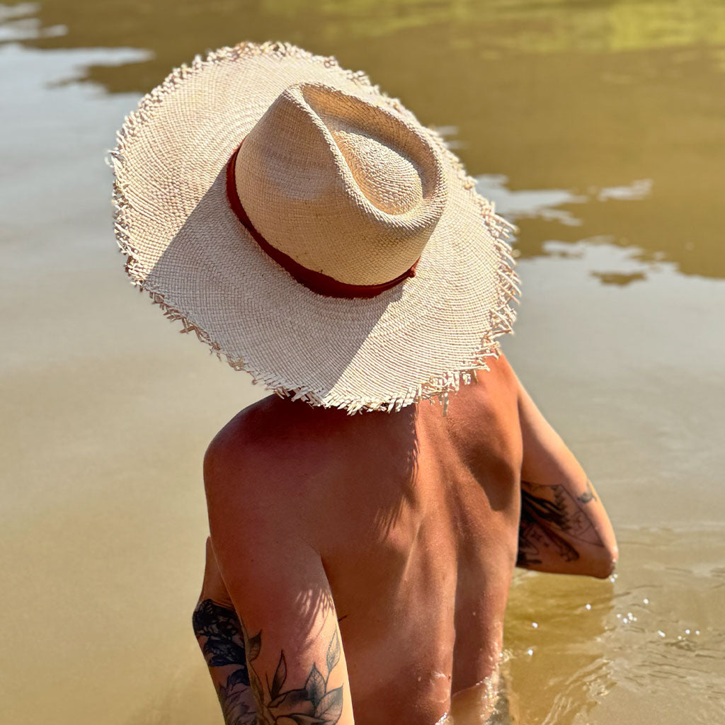 Person wearing a straw hat by a body of water