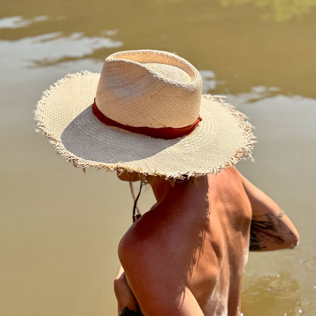 Person wearing a straw hat by a body of water