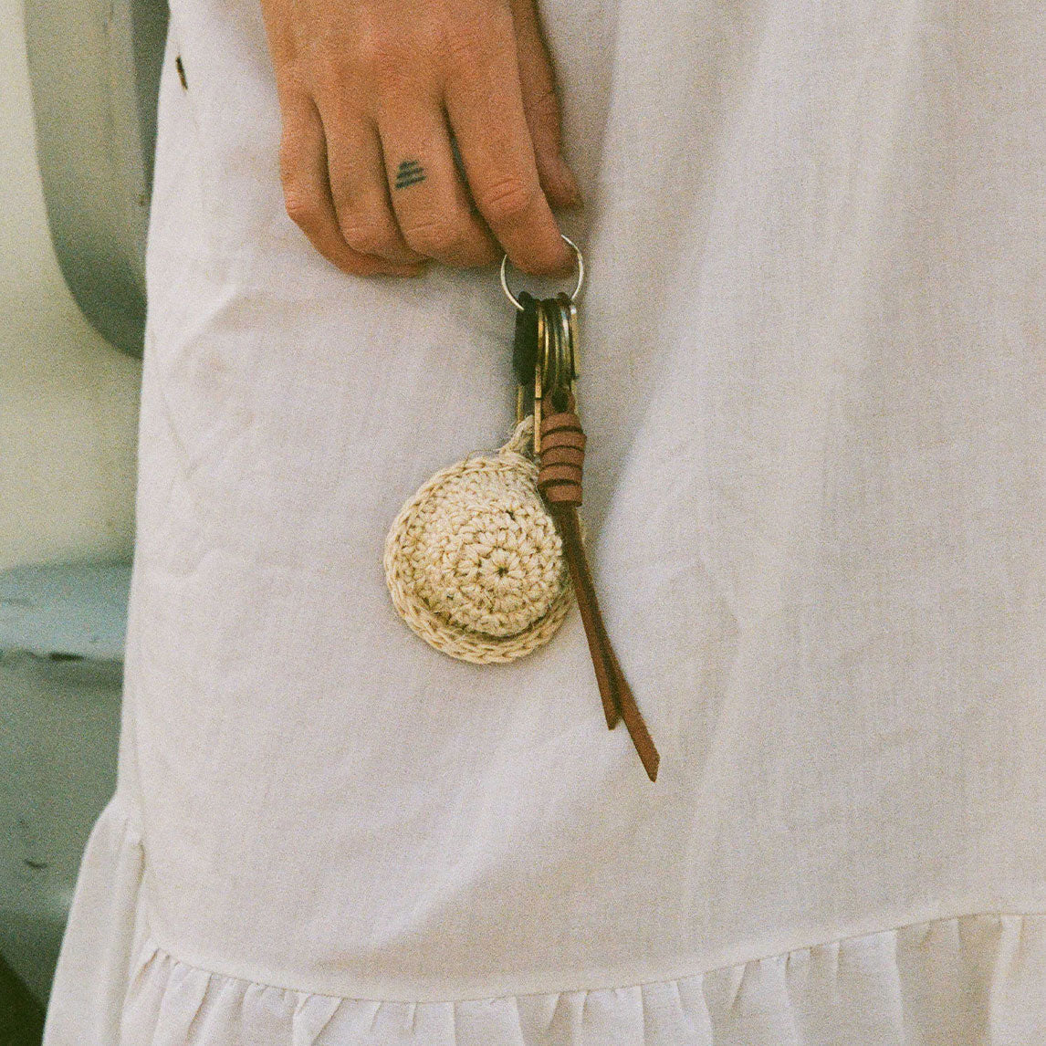 Person wearing a white dress with a woven keychain attached to it.